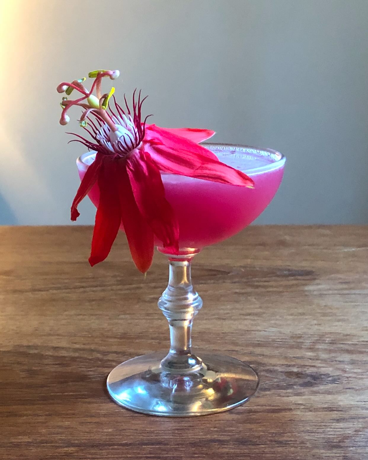 Pink coupe cocktail with passionflower garnish