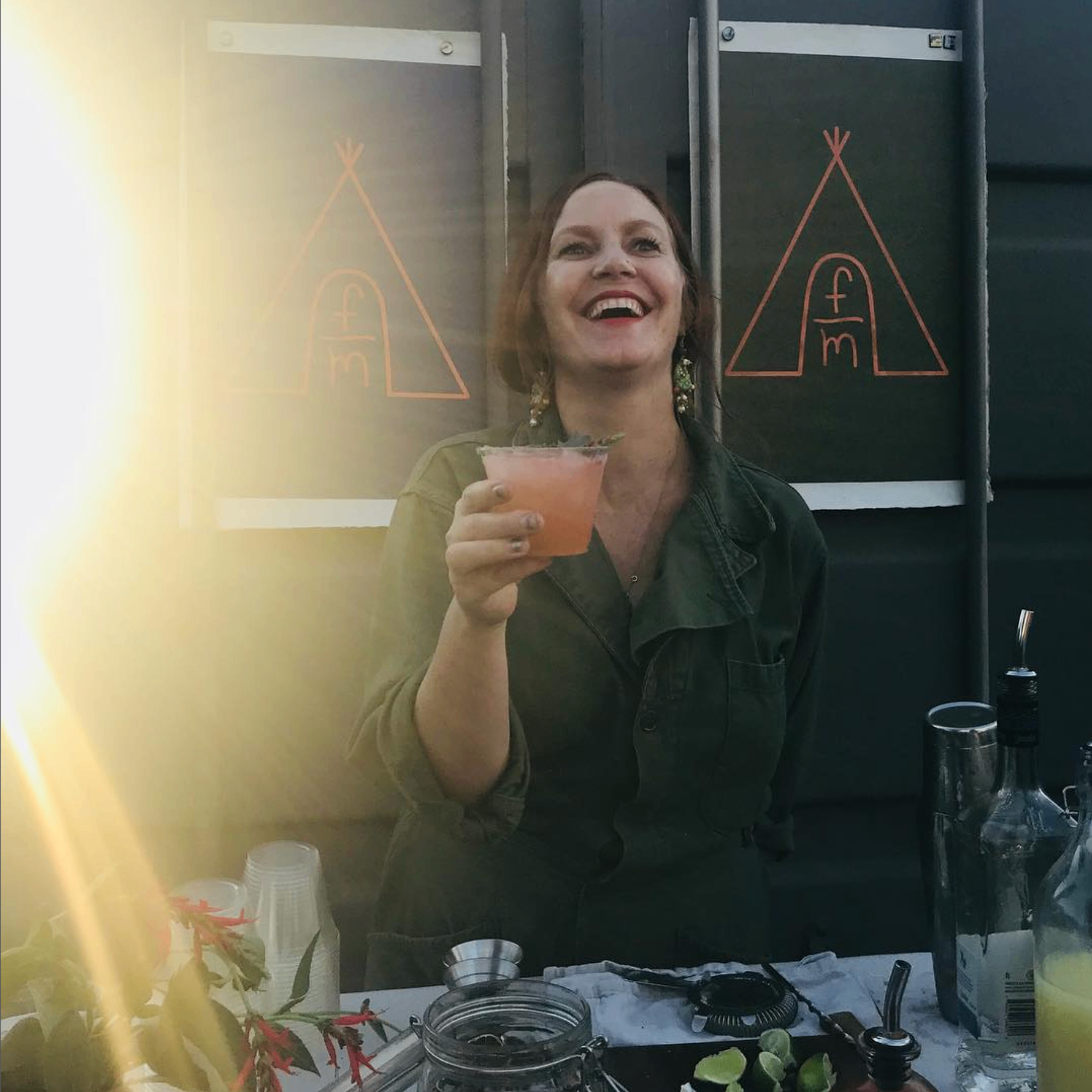 Sabi laughing while serving a fresh cocktail at golden hour